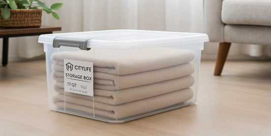 A clear 17 QT Citylife plastic storage box with beige towels neatly folded inside, featuring a white lid, placed on a wooden floor.